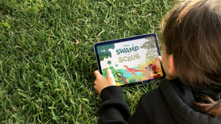 child with a tablet sitting on grass